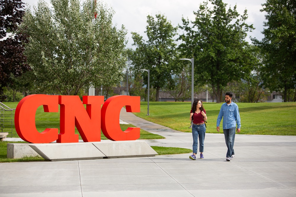 Students walking by CNC letters