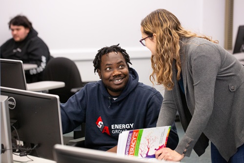 Student on computer getting help from professor