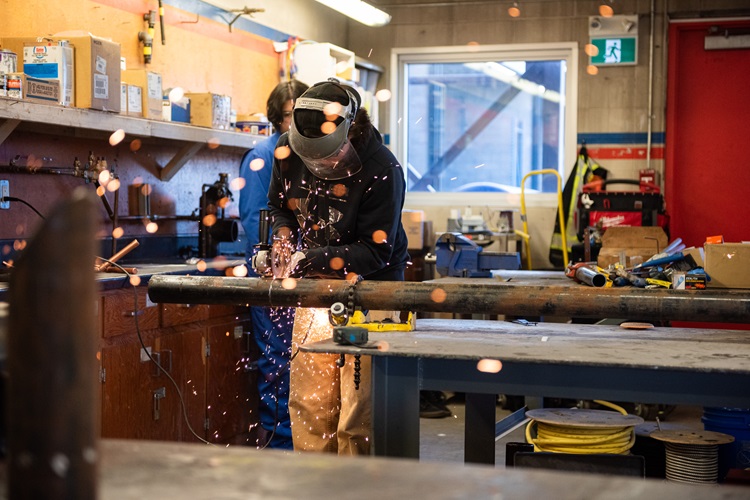 Pipe fitting student cutting a pipe with a saw