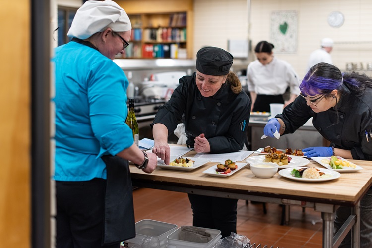 Three cooks plating food