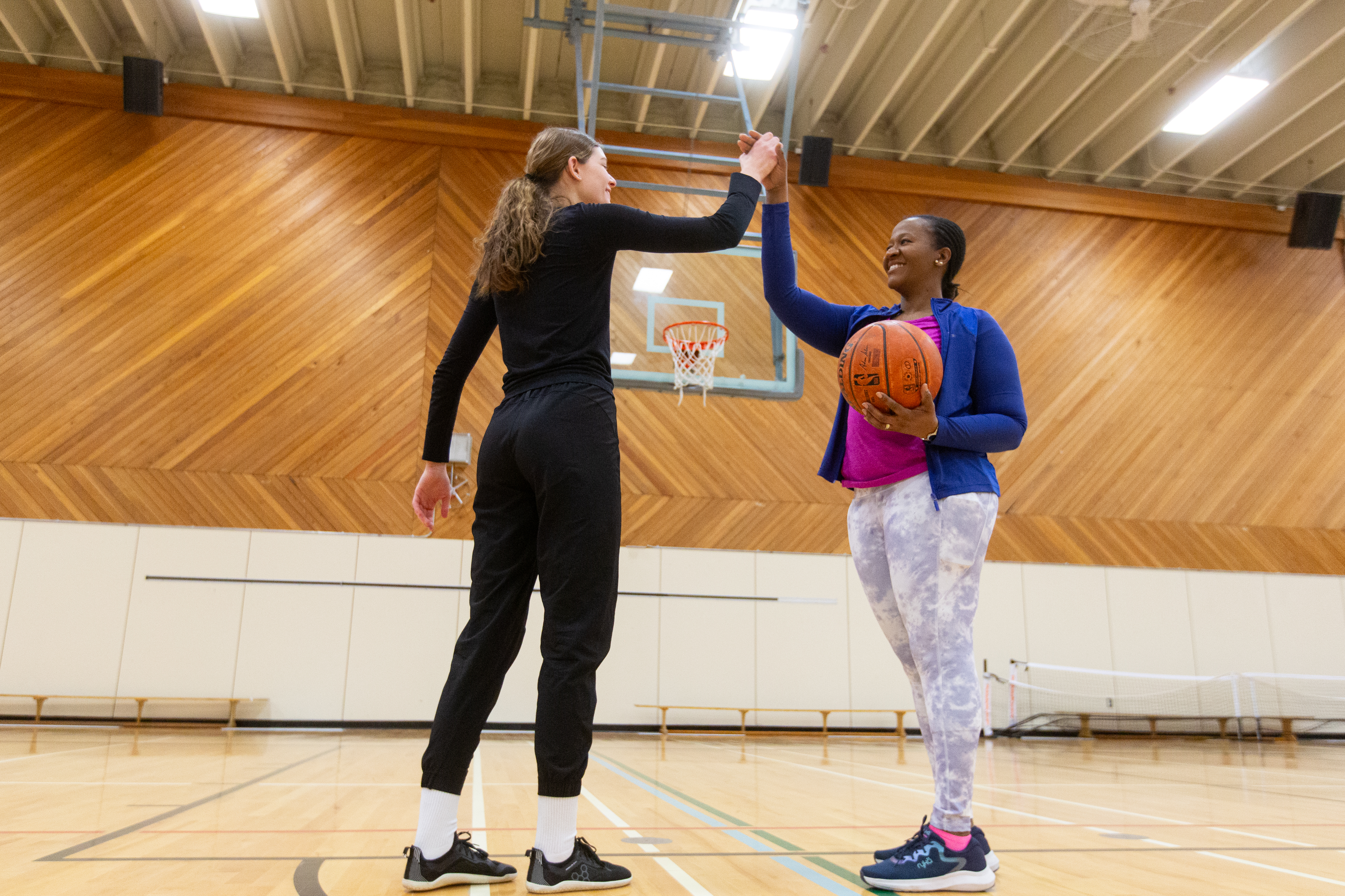 Two people high-fiving in a gym on a basketball court