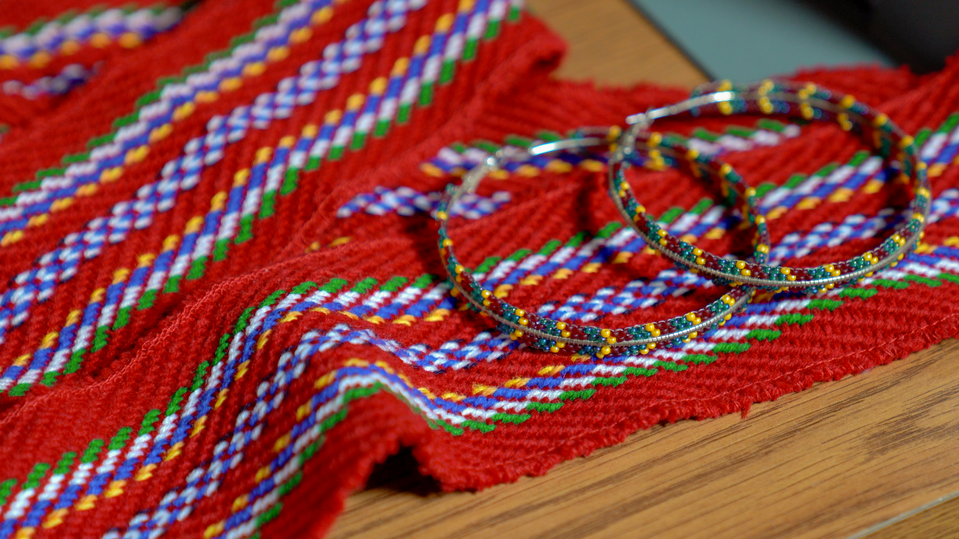 Hand beaded bracelets lying on top of hand woven sash