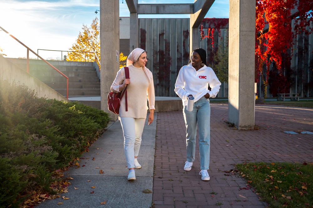 Two students walking in the CNC courtyard