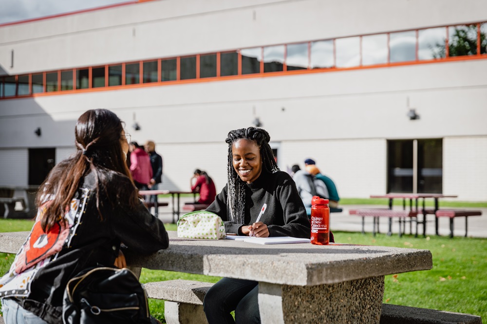 Two students study at a picnic table in the CNC courtyard