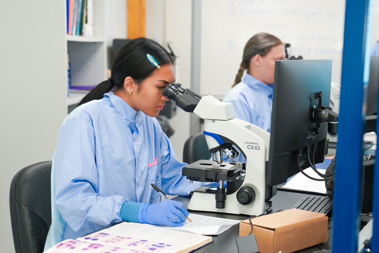 Student using microscope and taking notes in new CNC dry lab
