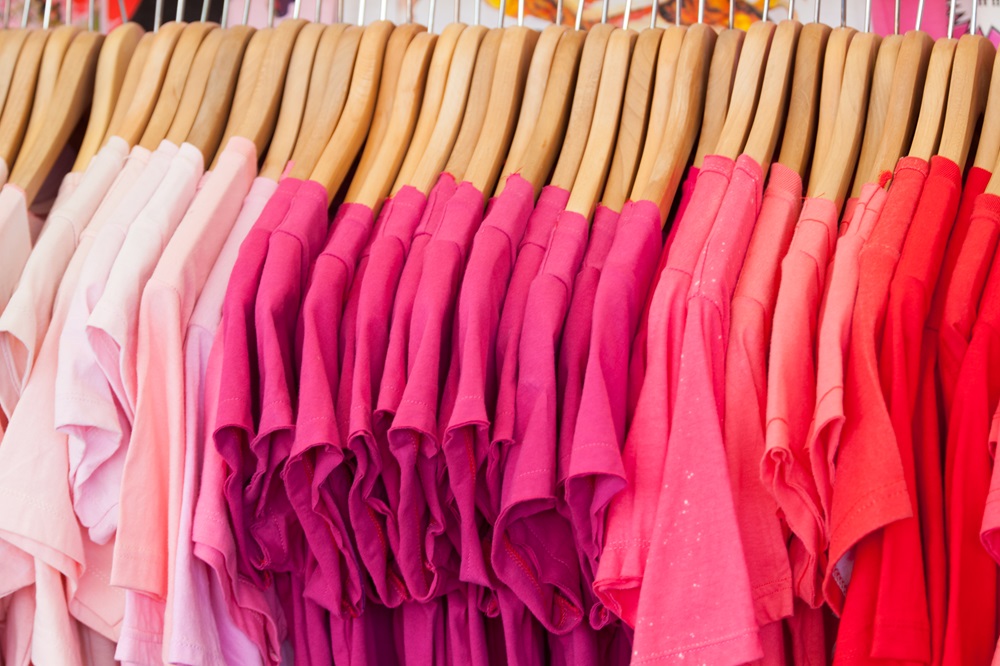 Many shades of pink shirts hanging on rack