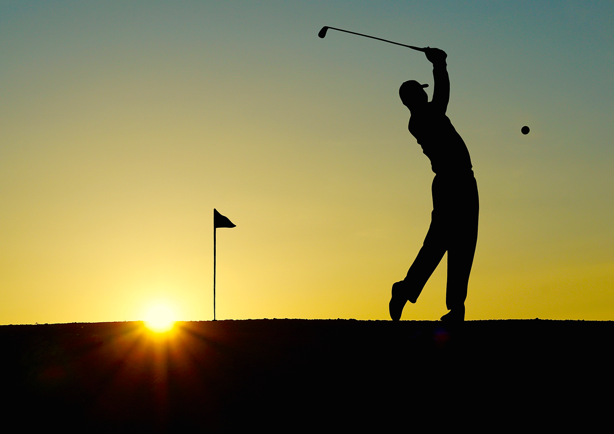 Silhouette of a golfer chipping the ball into the sunset
