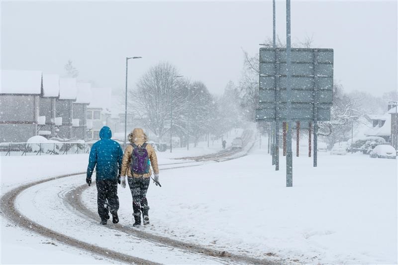 Two students walking away bundled up for the snowy weather