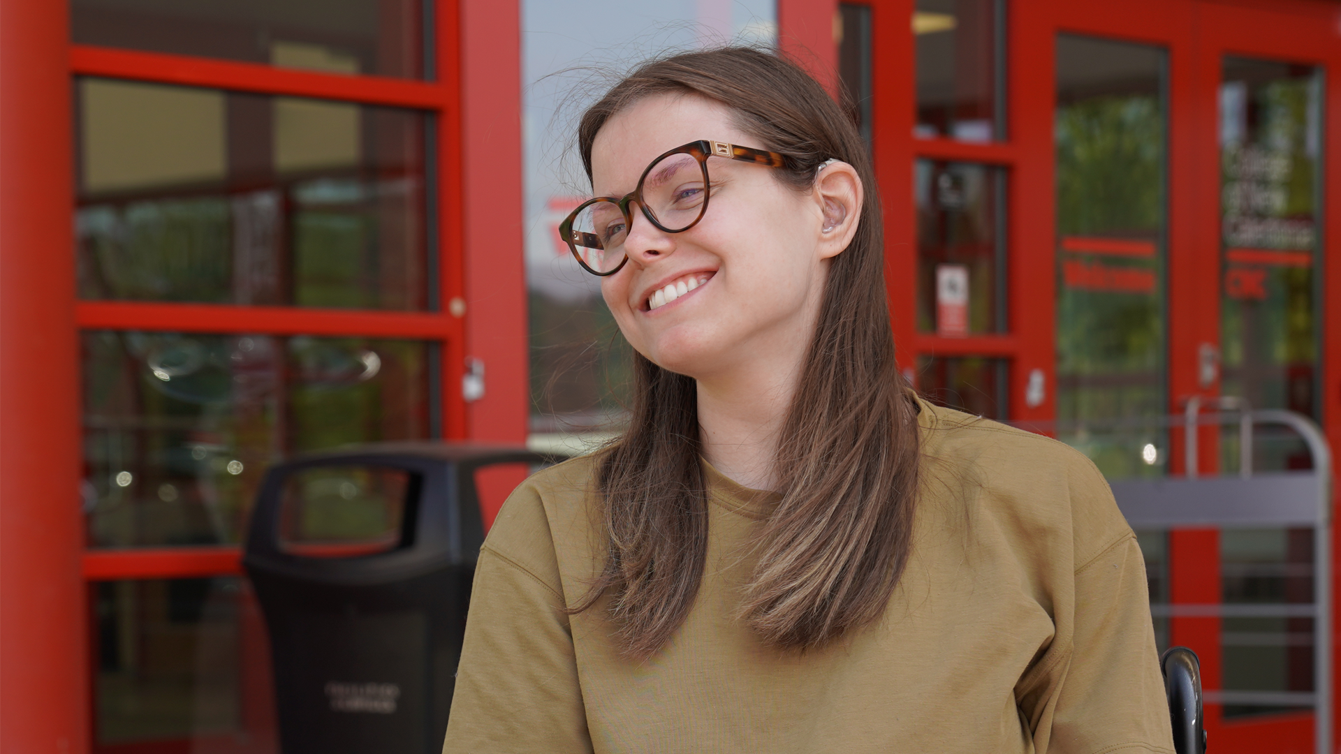 Brooke smiling at a friend in front of the college's main entrance