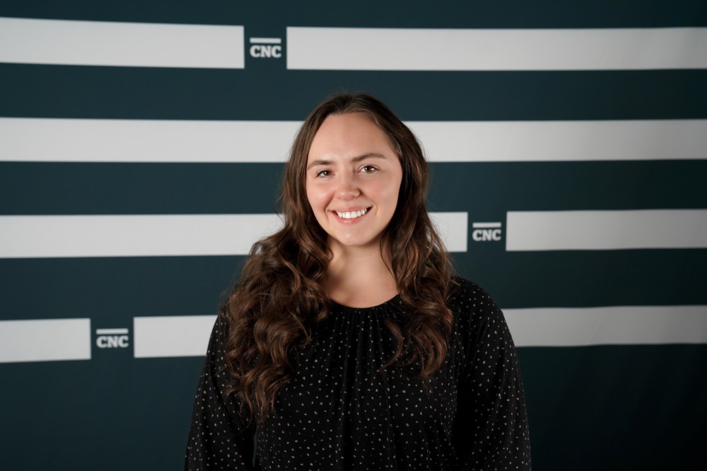 Kyndra smiling and standing in front of CNC backdrop