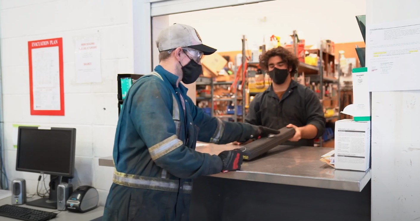 Student wearing coveralls getting parts from warehouse